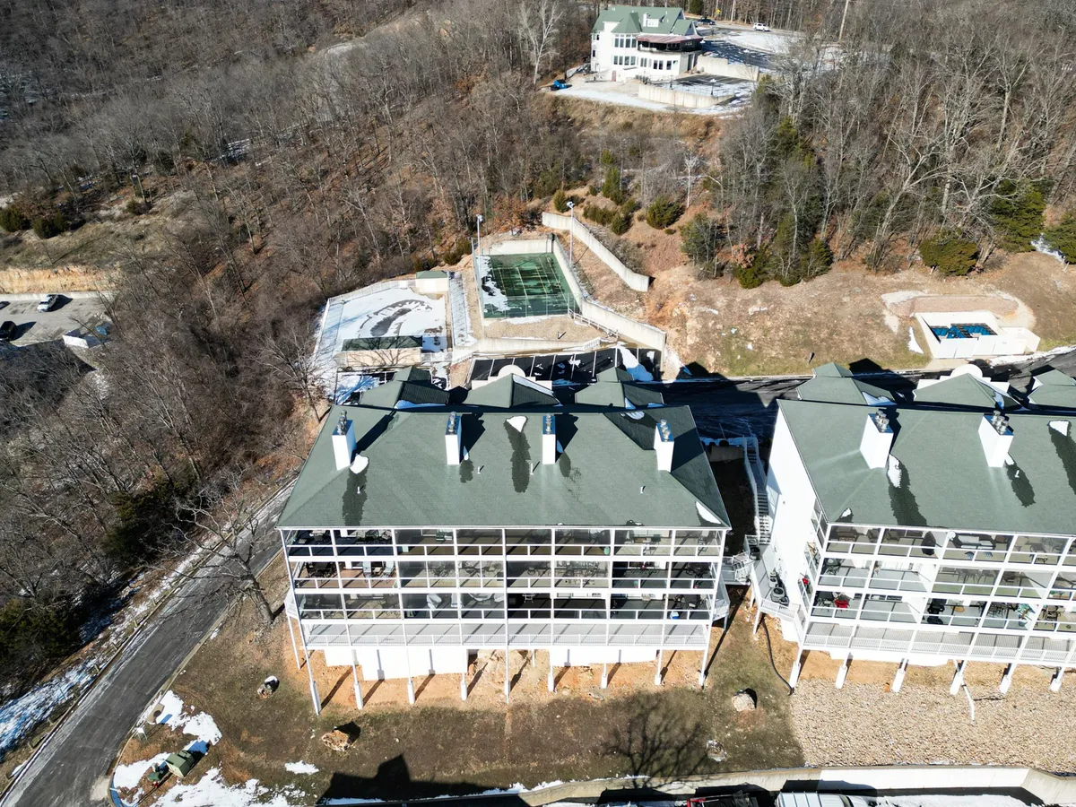 This image features the exterior of multi-story condo buildings overlooking the serene swimming pool area, with balconies facing the main channel and lush surrounding landscape. The pool area is inviting for relaxation, and the balconies offer sweeping views perfect for sunset watching or morning coffee.