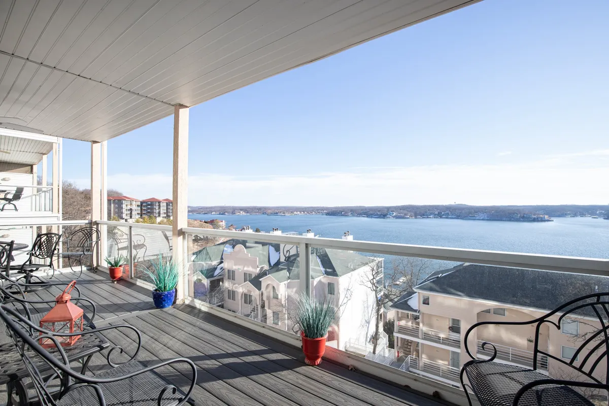 The image showcases a serene lake view from a private balcony, featuring comfortable outdoor seating perfect for relaxing, socializing, or enjoying a meal. The balcony railing frames a stunning expanse of water, inviting guests to unwind while taking in sunrise vistas, golden sunsets, or stargazing in the evening.