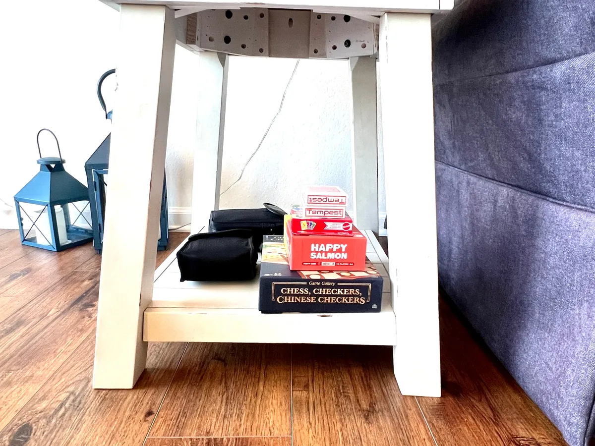 A bright, inviting room centered around a white table set up with board games and a lantern, surrounded by comfortable seating. The playful arrangement invites guests to partake in group activities and shared fun.