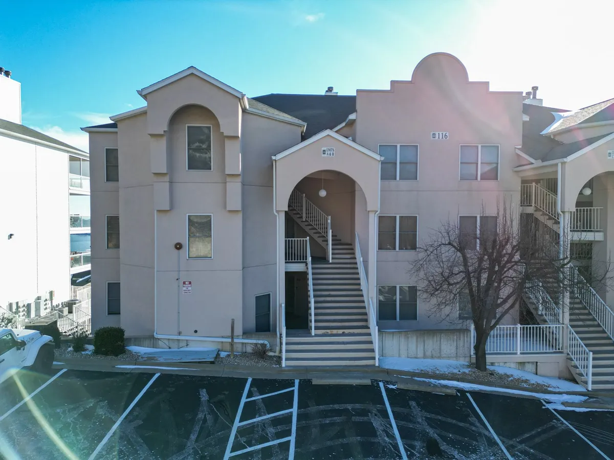 A welcoming view of the community’s arched entryway, staircases, and balconies, suggesting a friendly neighborhood atmosphere. The scene hints at communal gathering spaces and open areas where families can come and go with ease.