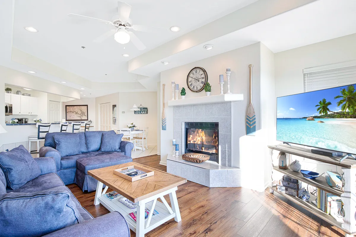 A cozy, family-friendly living room featuring a large sectional sofa, a central coffee table, a fireplace, and a large TV. Soft lighting, warm tones, and inviting decor create the perfect environment for group relaxation and shared activities.