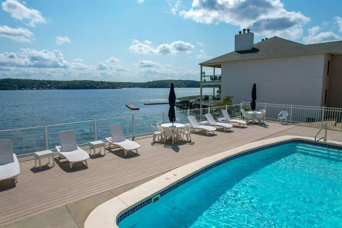 A serene exterior setting with a sparkling swimming pool beside an array of lounge chairs, all overlooking the lake’s edge. The pool area is inviting and suggests both active and leisurely pursuits, from swimming laps in the morning to social gatherings at sunset. The waterfront view reinforces the proximity to lake activities and the allure of the outdoors.
