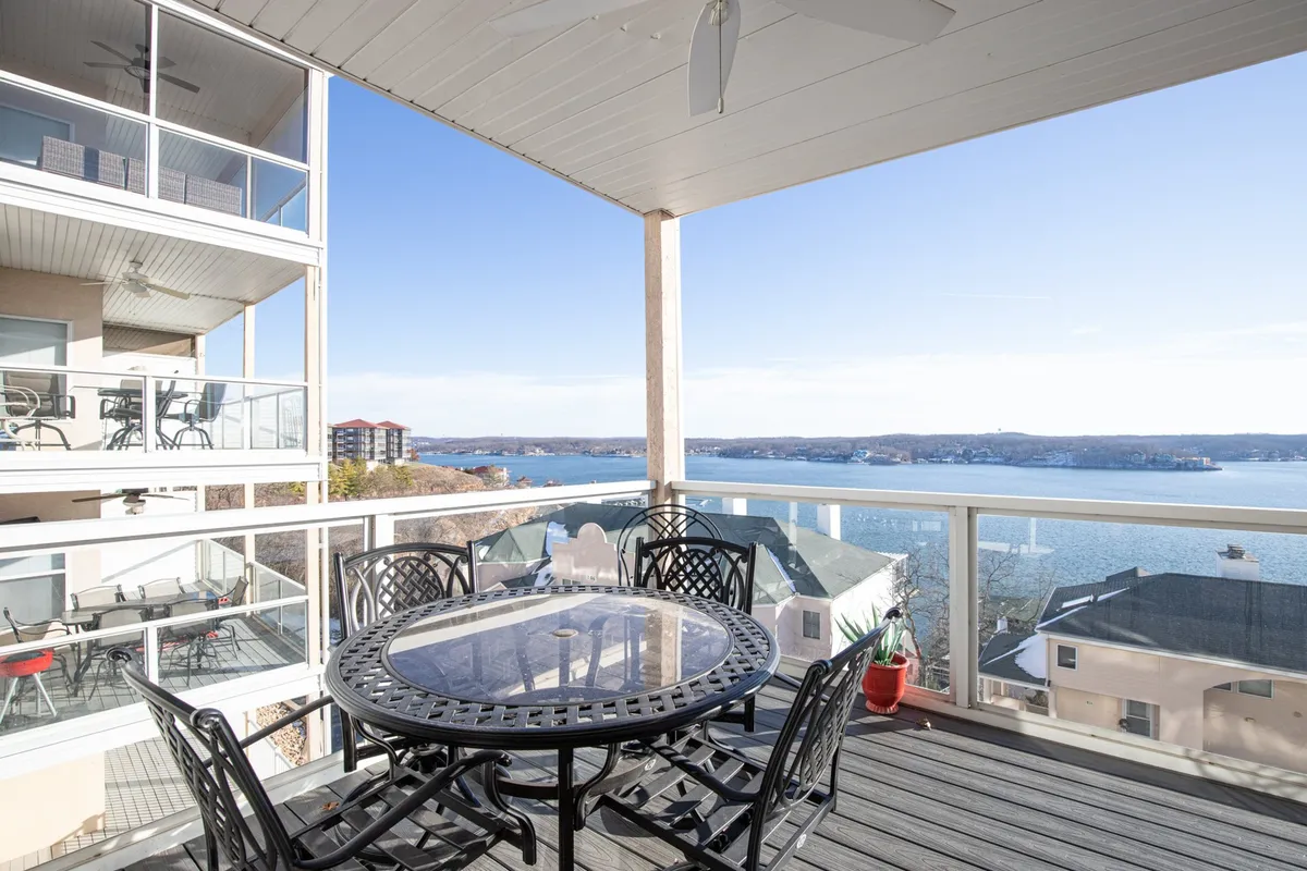 A serene covered balcony with an outdoor dining table and chairs, framed by a classic railing and boasting direct views over the lake. The perfect spot for morning coffee, sunset watching, or outdoor entertaining.